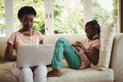 Mother and daughter using laptop and digital tablet Mother and daughter using laptop and digital tablet