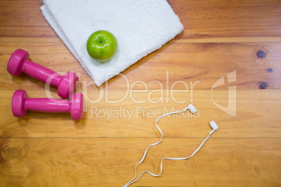 Gym equipment and apple kept on wooden floor