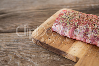 Raw beef ribs on wooden tray against wooden background