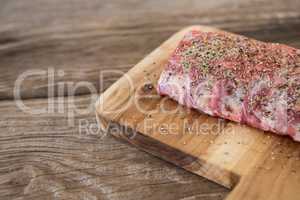 Raw beef ribs on wooden tray against wooden background