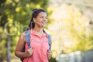 Smiling schoolgirl standing with schoolbag in campus