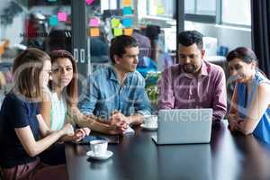 Businesspeople having discussion over laptop in office