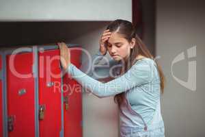 Sad schoolgirl standing in locker room