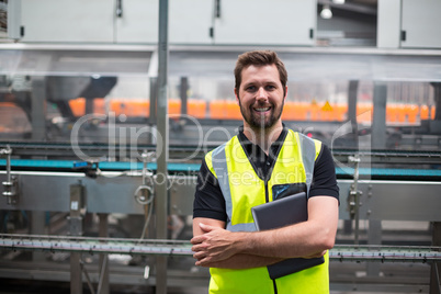 Portrait of smiling factory worker standing with a digital tablet