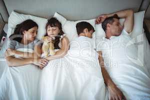 Parents and kids sleeping on bed