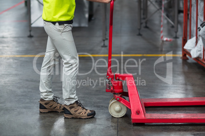Factory worker pulling trolley in factory
