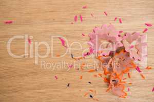 Colored pencils shavings on a wooden background