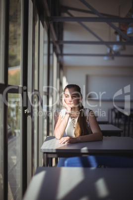 Thoughtful schoolgirl sitting in classroom