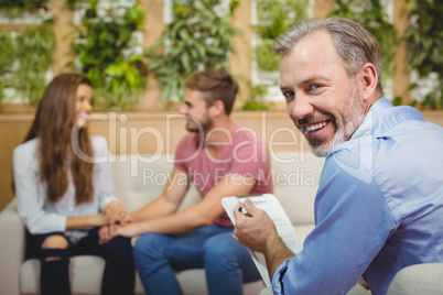 Portrait of smiling doctor with couple in background