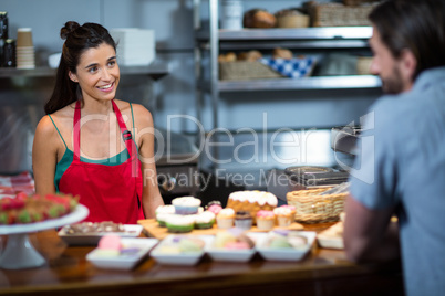 Smiling female staff interacting to customer at counter