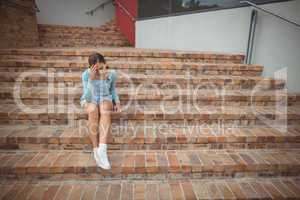 Sad schoolgirl sitting alone on staircase