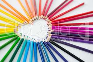 Colored pencils arranged in heart shape on white background