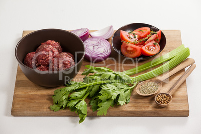 Minced beef and ingredients on wooden board
