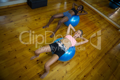 Two fit women performing pilate on exercise ball