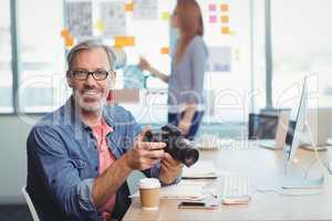 Male graphic designer holding digital camera