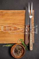 Knife and fork on wooden board