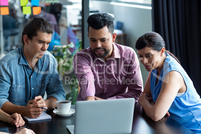 Businesspeople having discussion over laptop in office