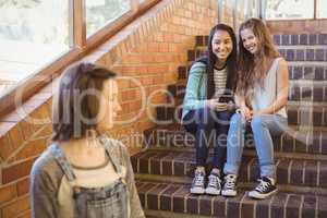 School friends bullying a sad girl in school corridor