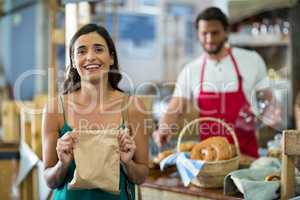 Portrait of smiling female customer showing parcel bag at counter