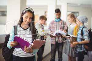 Schoolgirl standing in corridor reading notebook