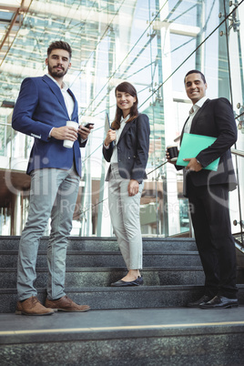 Portrait of business executives standing on stairs outside platform