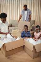 Parents and kids opening cardboard boxes in living room