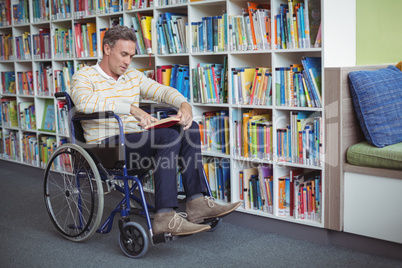 Attentive disabled school teacher reading book in library