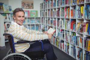 Portrait of disabled school teacher holding book in library