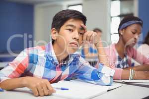 Thoughtful schoolboy sitting in classroom