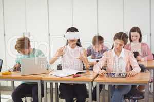 School girl sitting in classroom using virtual reality headset