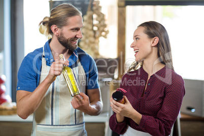 Shop assistants interacting while holding olive oil and pickle bottles