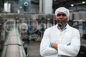Factory engineer standing with arms crossed in bottle factory