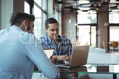 Executives using laptop and digital tablet in cafÃ?Â©