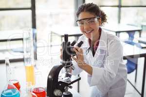 Portrait of schoolgirl experimenting on microscope in laboratory
