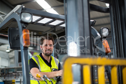 Portrait of smiling factory worker driving forklift