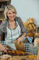 Saleswoman packing parcel for customer at counter