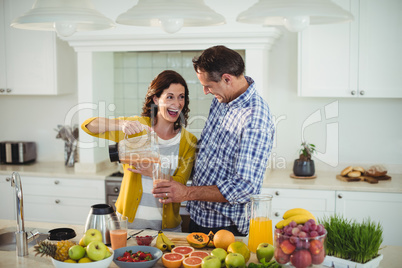 Happy couple preparing smoothie in kitchen