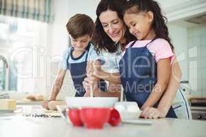 Mother and kids mixing the dough while preparing cookies