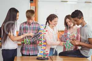 Happy school kids experimenting molecule model in laboratory