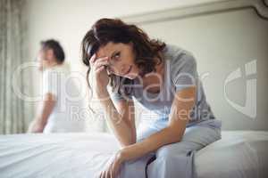 Tensed woman sitting on a bed