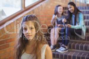 School friends bullying a sad girl in school corridor