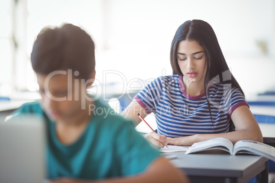 Attentive schoolgirl studying in classroom