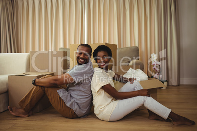 Portrait of couple sitting back to back in living room