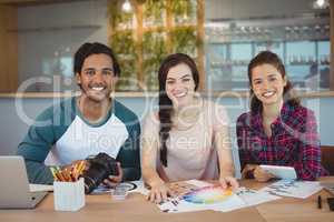 Portrait of happy graphic designers sitting at desk