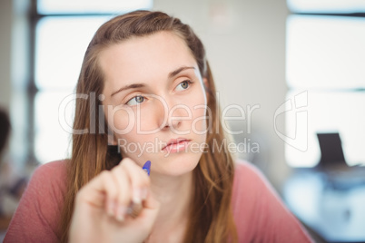 Thoughtful school girl doing homework in classroom