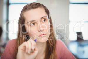 Thoughtful school girl doing homework in classroom