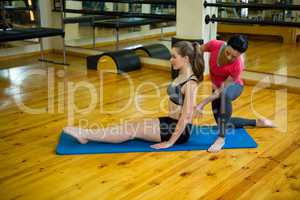 Female trainer assisting woman with exercise