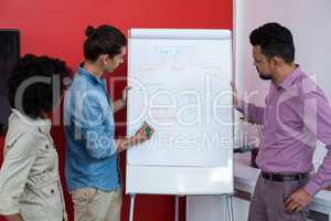 Business executives discussing over flip chart during meeting