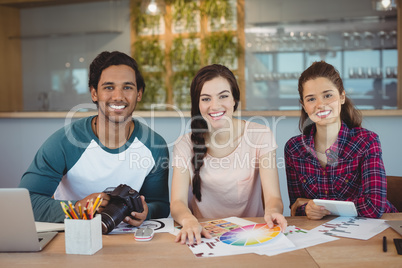 Portrait of happy graphic designers sitting at desk