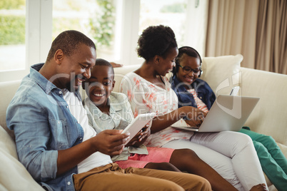 Parents and kids using laptop and digital tablet on sofa